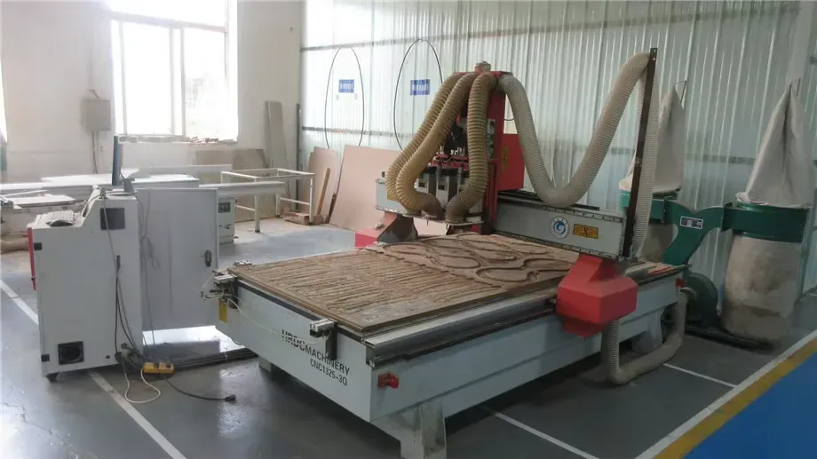 A CNC router cutting custom scratcher shapes from corrugated board.