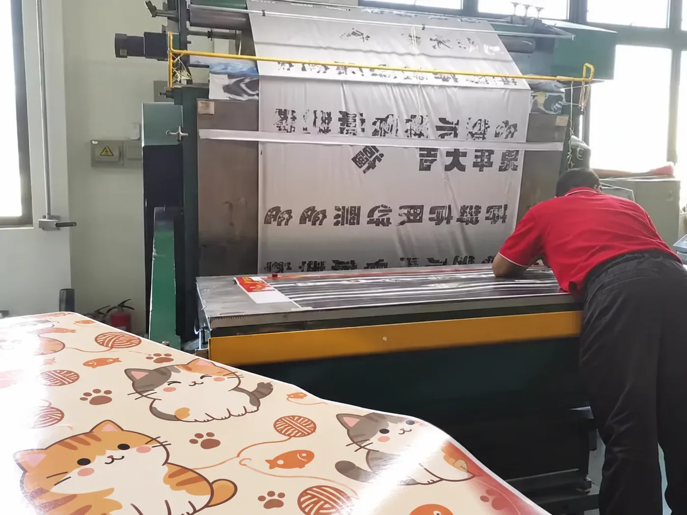 A press operator checking vivid cat artwork as freshly printed scratcher sheets come off the line.